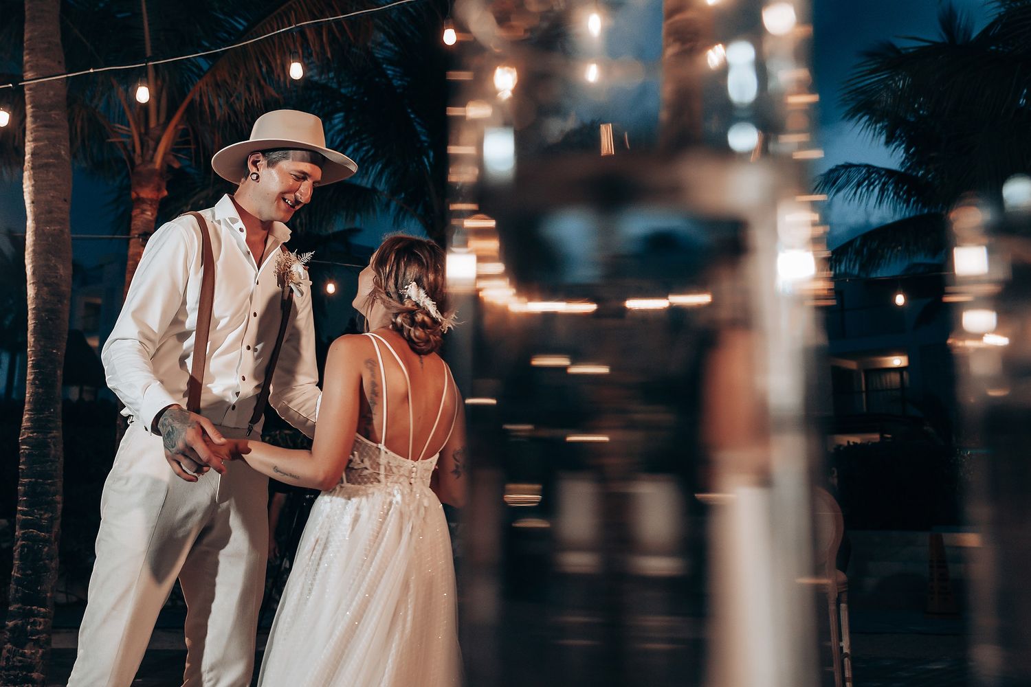 Evening beach reception with string lights illuminating palm trees.