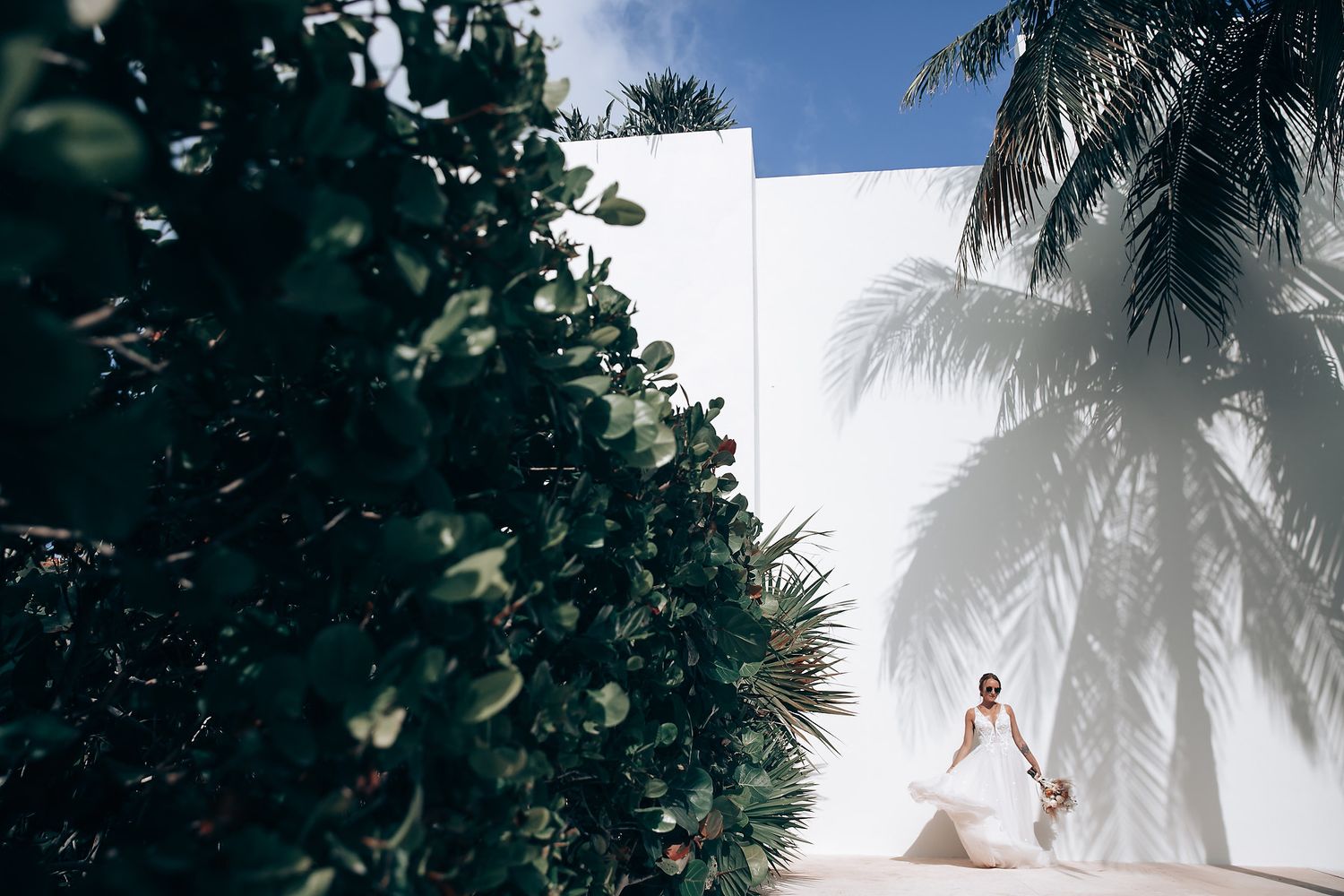 Palm trees frame an outdoor wedding ceremony setting against a bright sky.