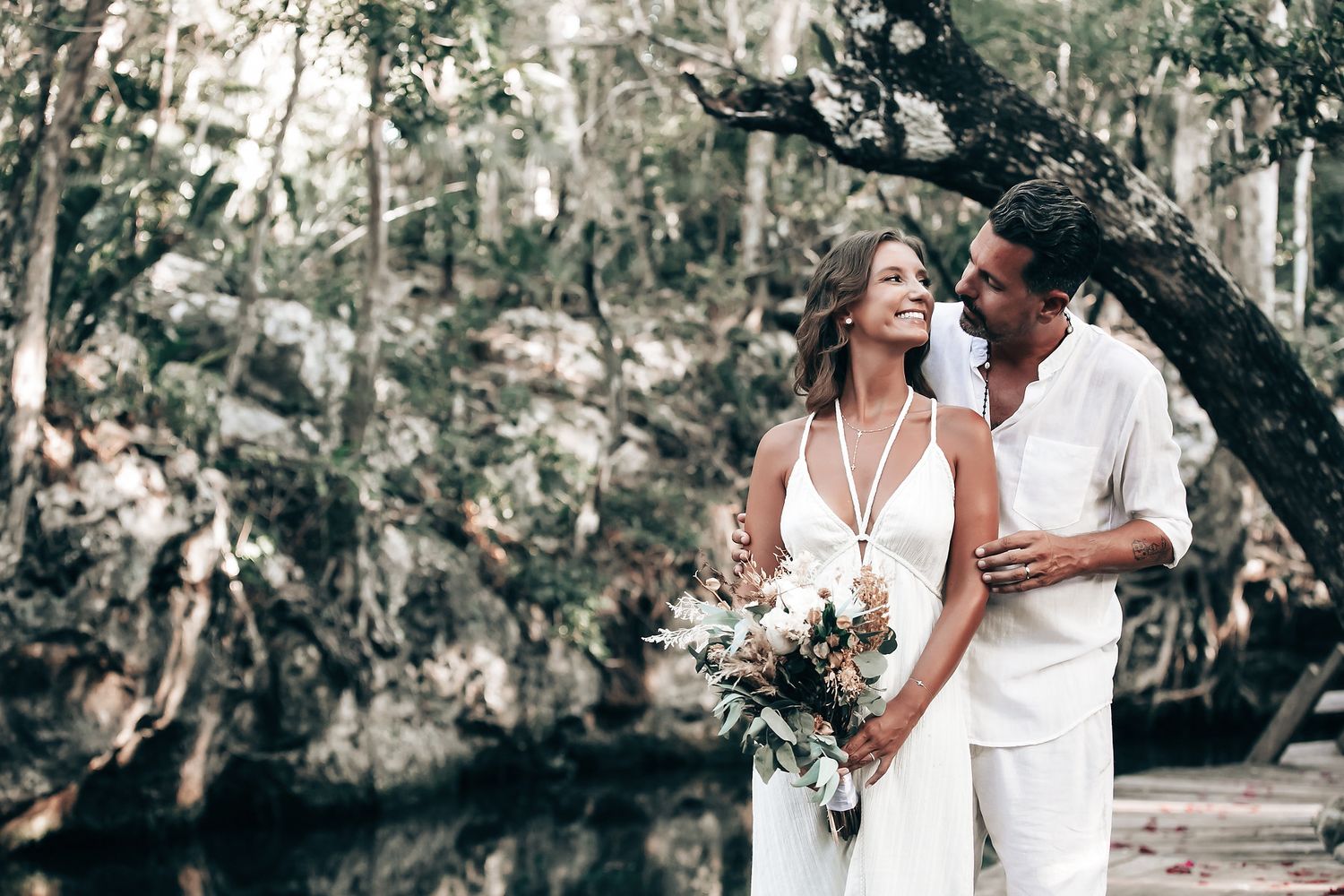 A couple exchanges vows or rings during a wedding ceremony in a natural, scenic setting.