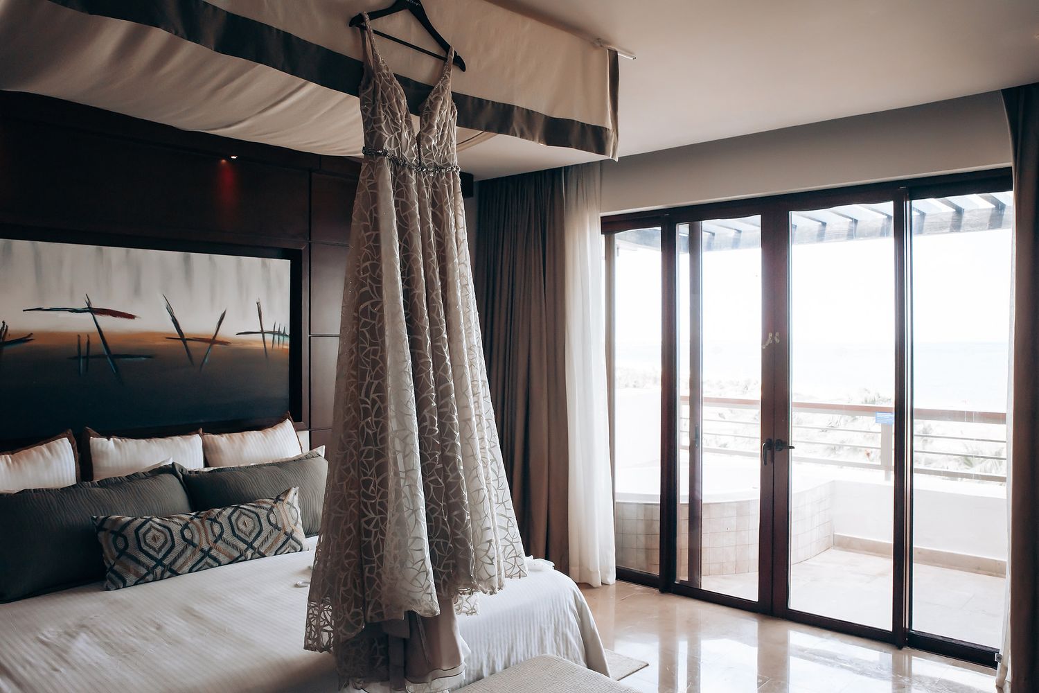A bedroom with a large, ornate bed and a sliding glass door leading to a balcony.