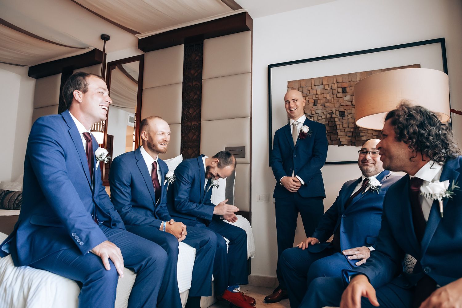 A group of men in suits sit and talk together in a room.