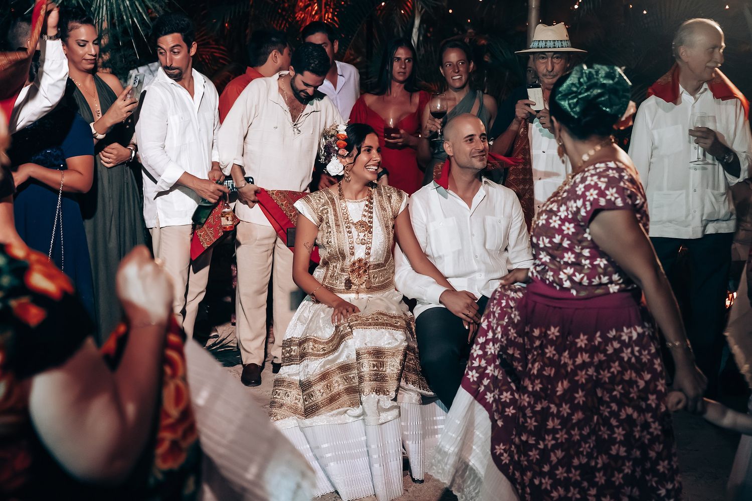 Wedding party dancing together on a dimly lit dance floor during an evening celebration.