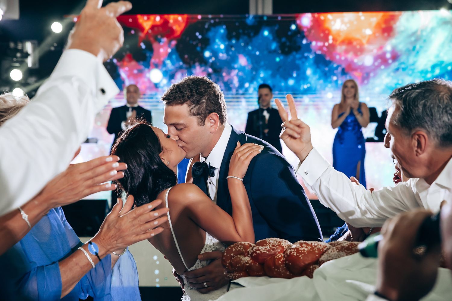 Wedding reception dance party with colorful galaxy-themed backdrop and lighting effects.
