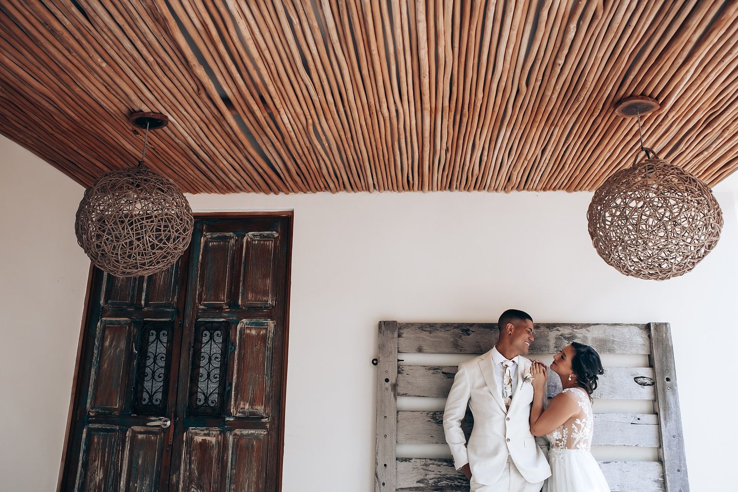 A rustic indoor venue with bamboo ceiling and stone walls creates an intimate wedding atmosphere.
