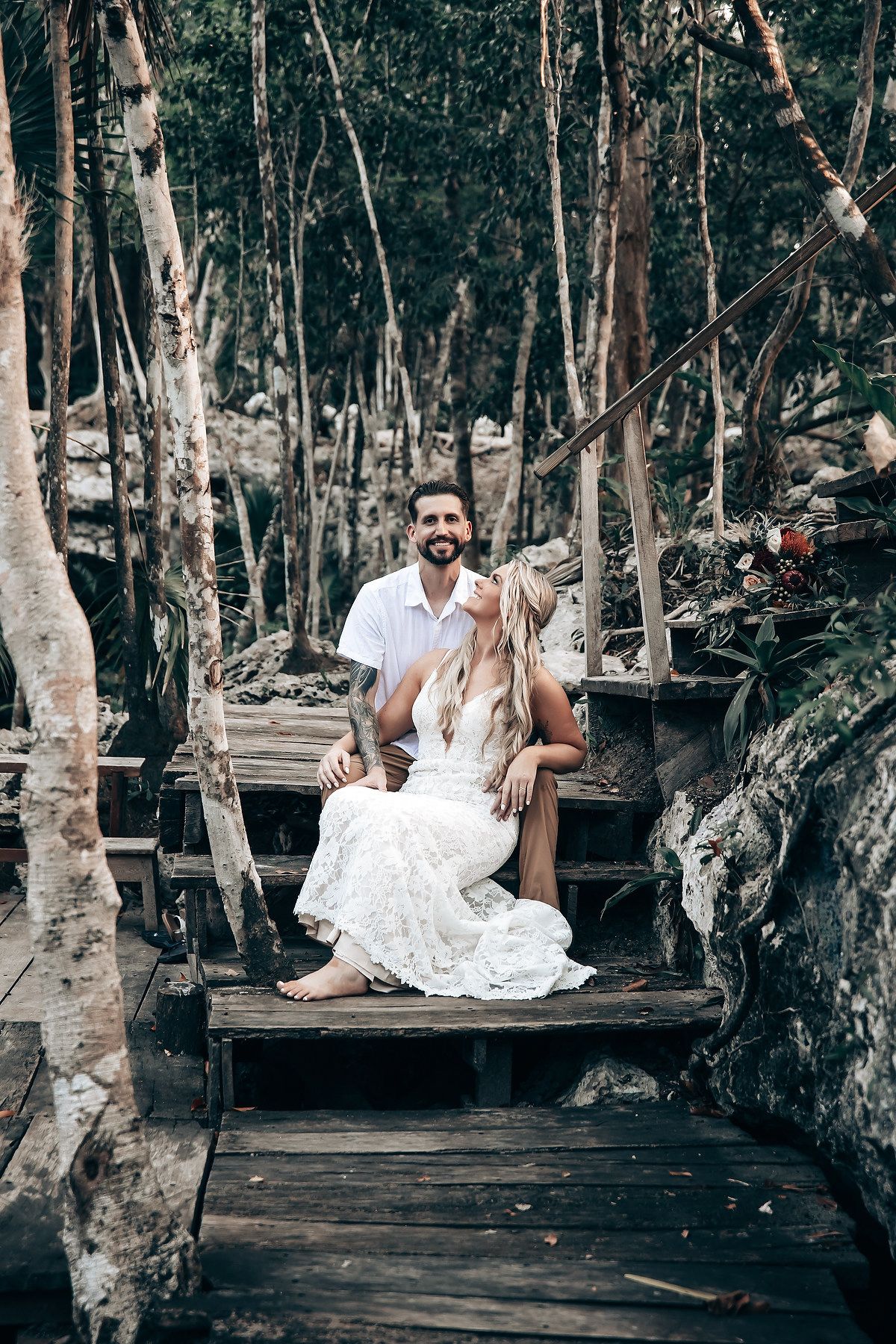 Couple seated on rustic wooden benches in a forest setting.
