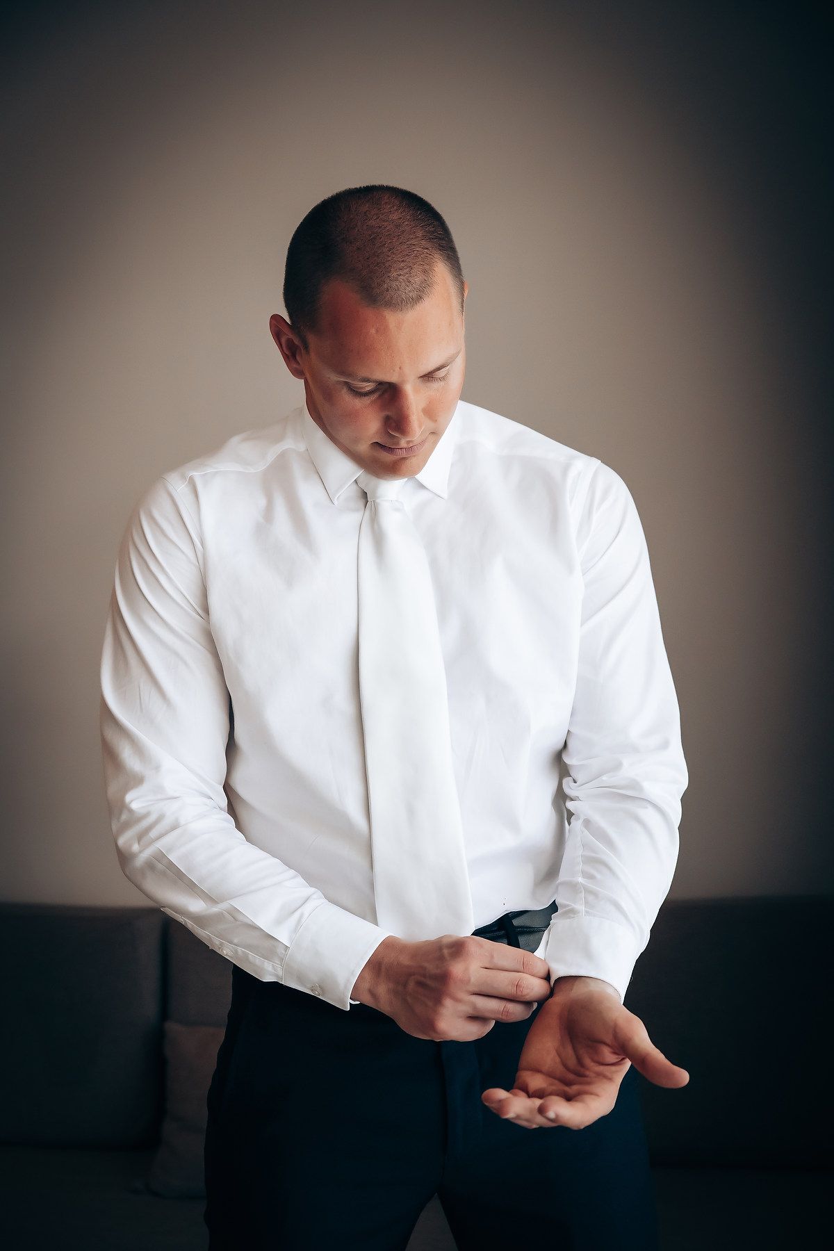 Person in white dress shirt adjusting cuffs during formal event preparation.