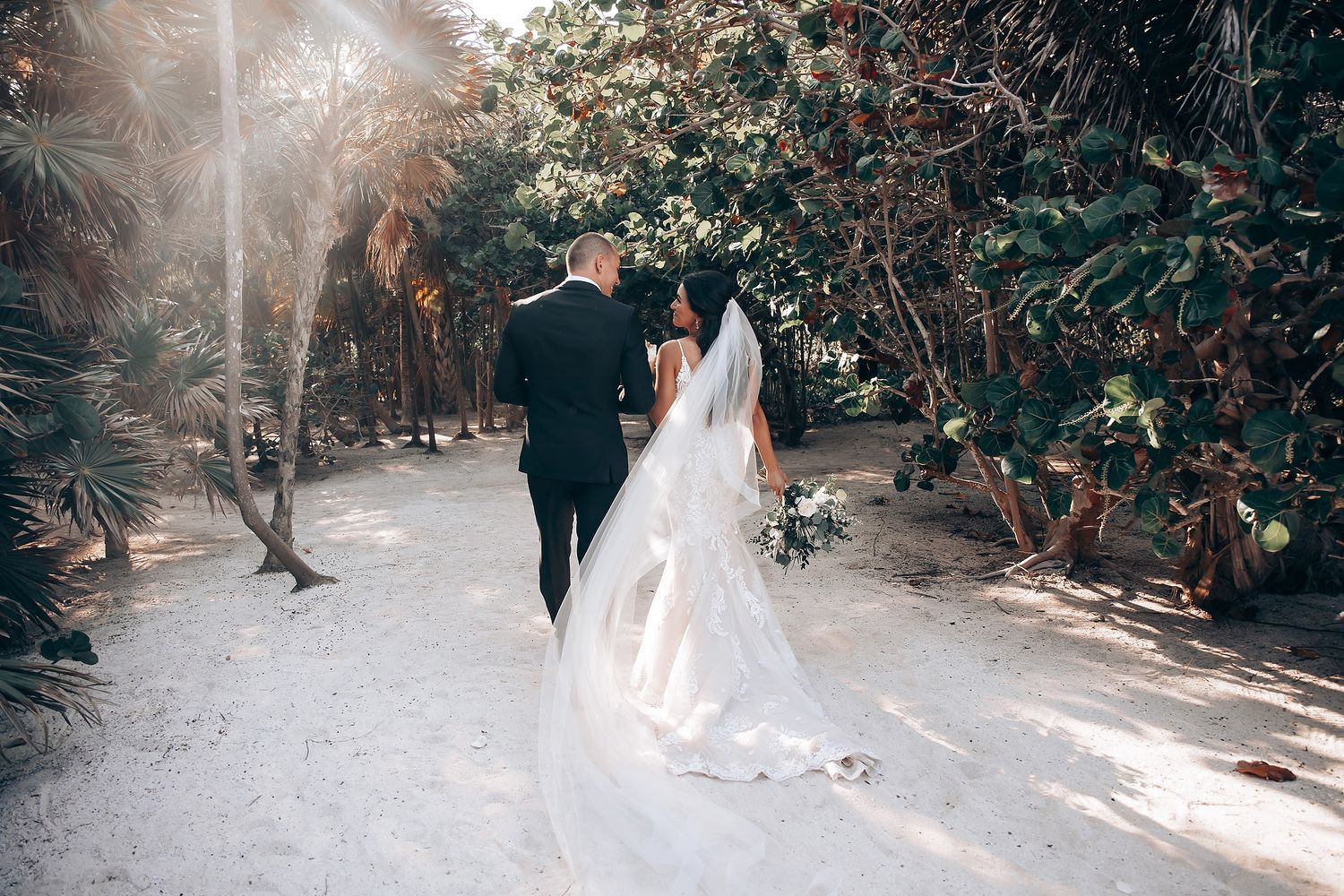Sunlit garden pathway decorated for a wedding ceremony with natural foliage and dappled light.
