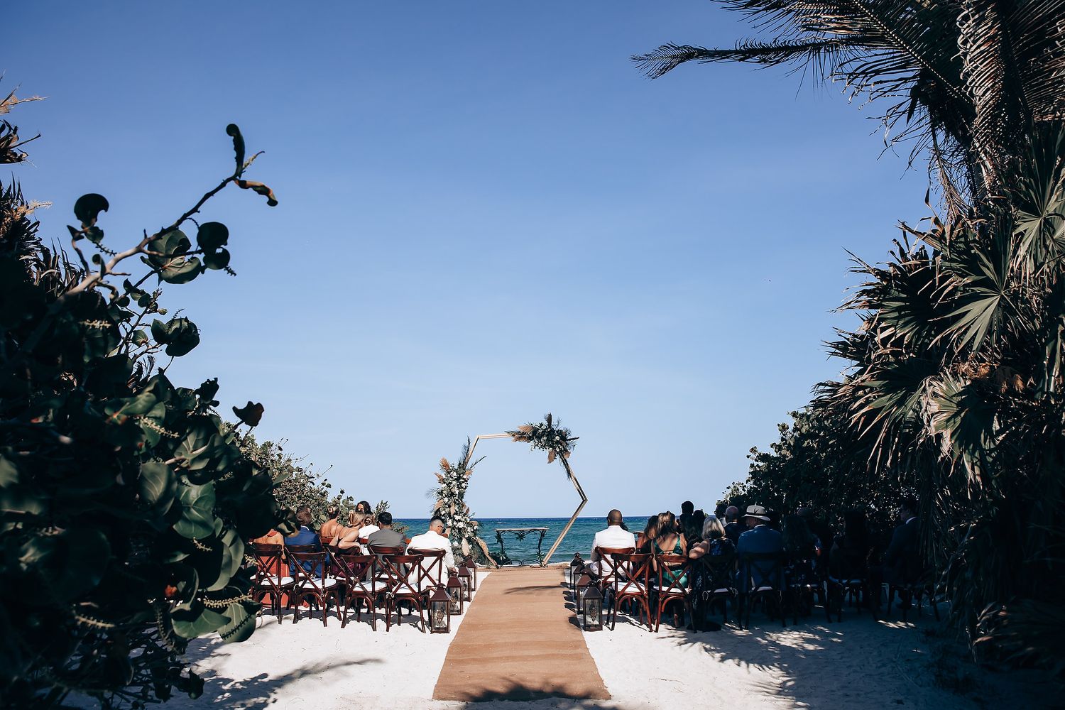 Beachfront wedding ceremony setup with palm trees and ocean views.