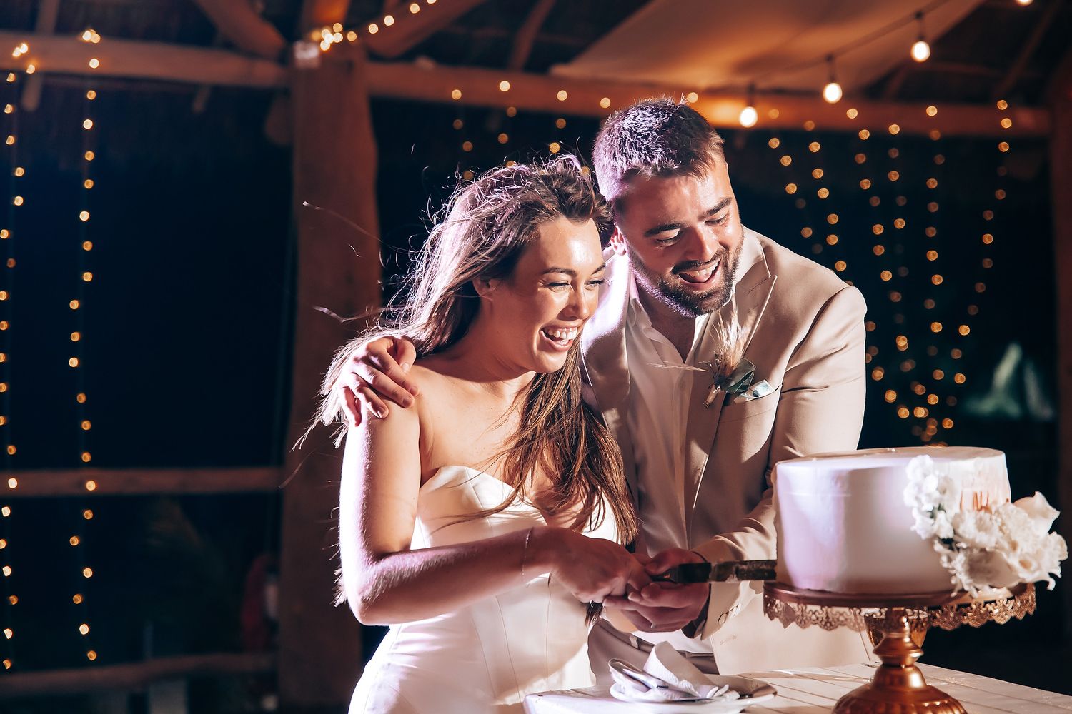 Romantic wedding reception scene with dancing couples and string lights creating an intimate atmosphere.