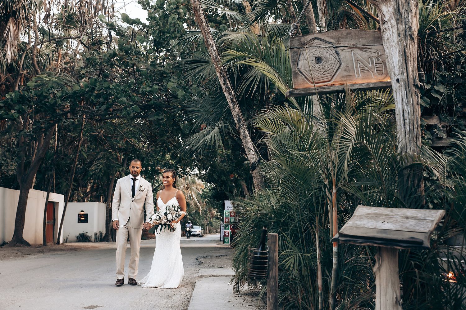 Wedding ceremony setup in a lush tropical garden with white chairs and natural greenery.