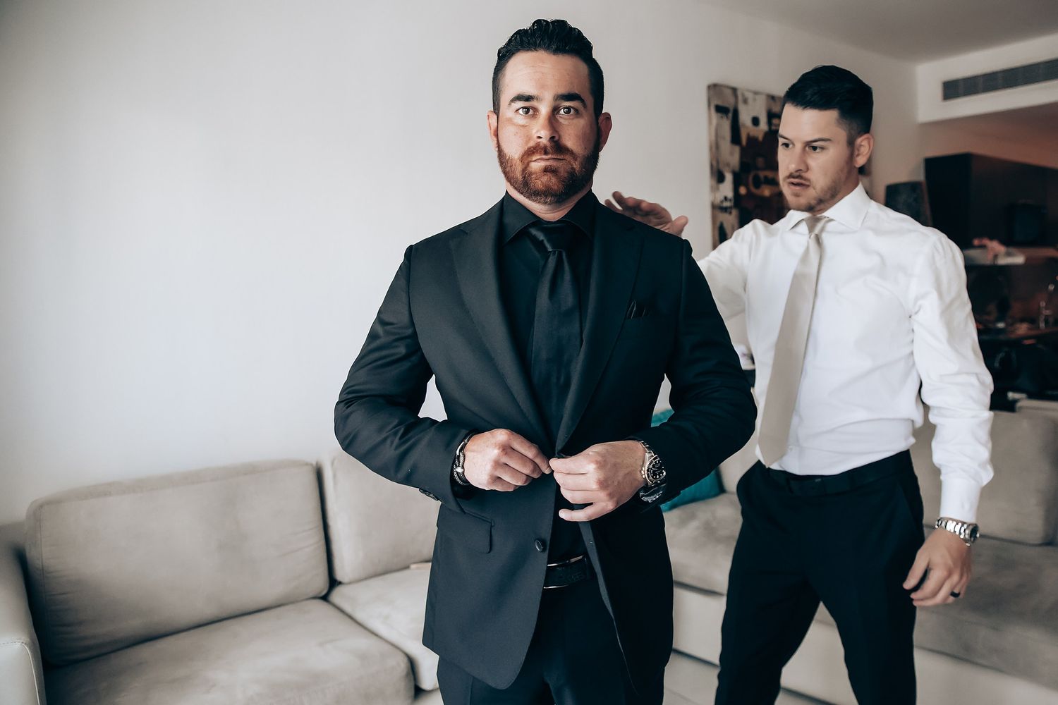 Groomsmen in black suits chatting before wedding ceremony.