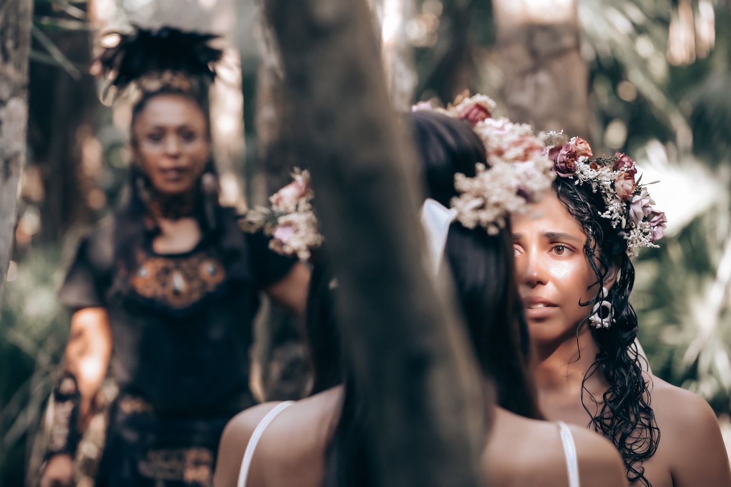 A person in dark attire stands in soft focus with floral elements creating an ethereal portrait composition.