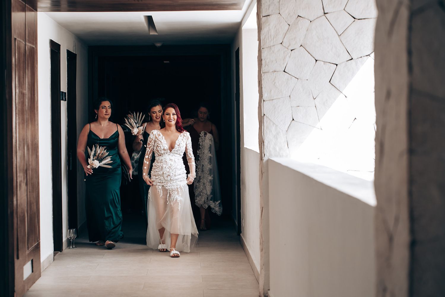 A group of people walk down a white hallway with geometric patterns on the wall.