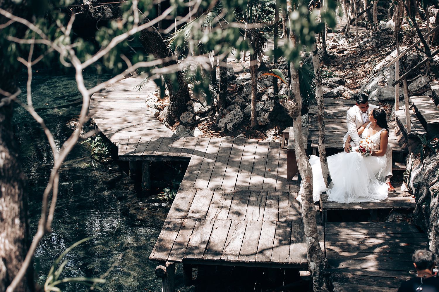 An outdoor wedding ceremony setup with wooden walkways in a natural forest setting.