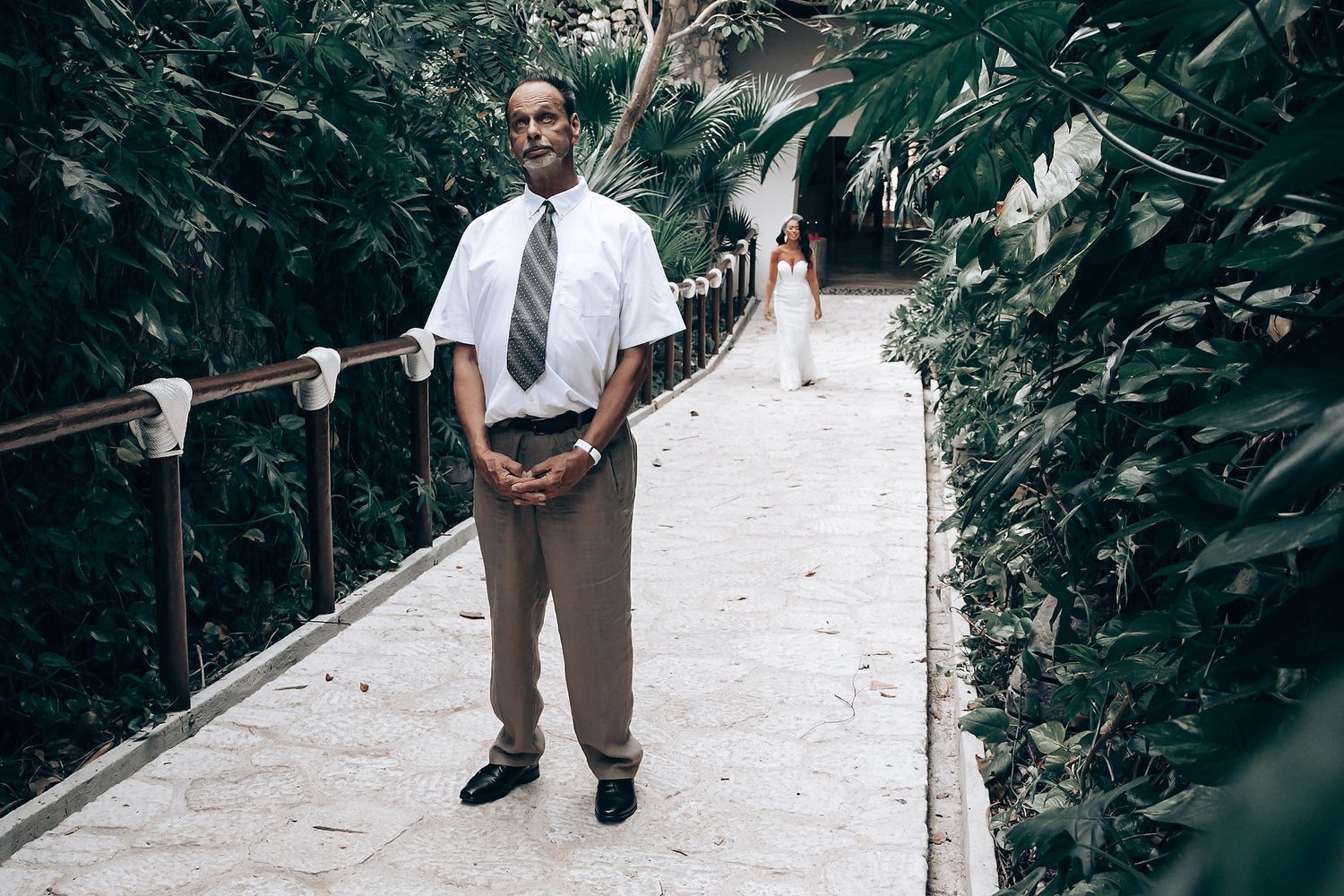 Security staff in formal attire stands guard on a garden pathway.