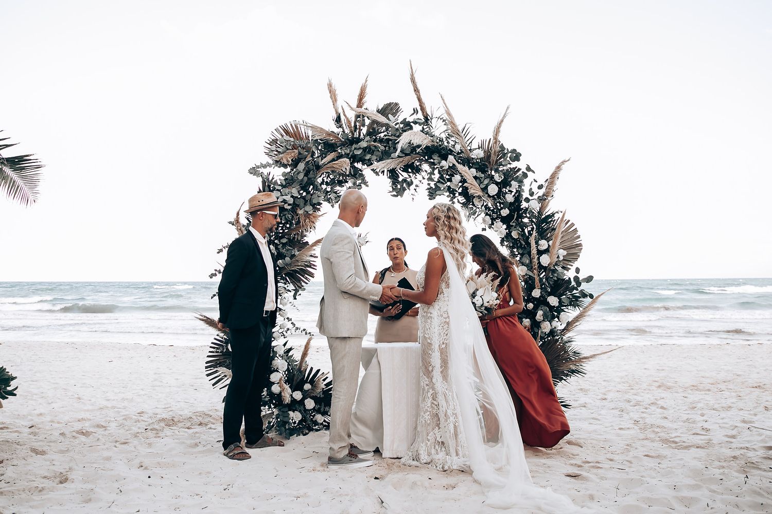 Beach wedding ceremony setup with floral arch and ocean backdrop.
