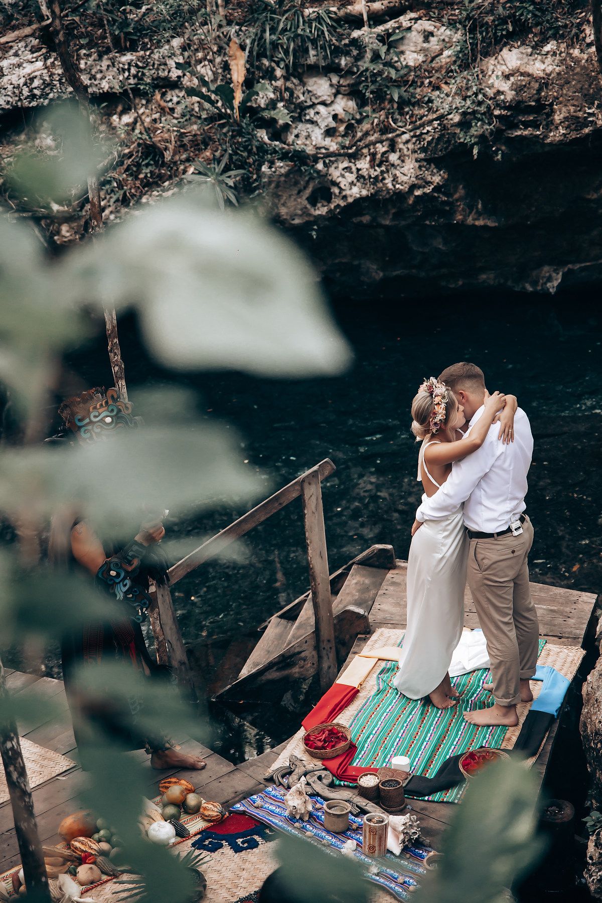 Romantic moment shared on decorated wooden platform overlooking cave waters.