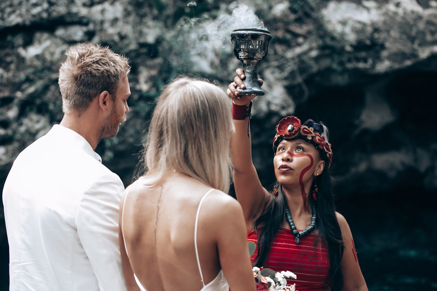 Outdoor wedding ceremony in a wooded area with natural sunlight filtering through the trees.