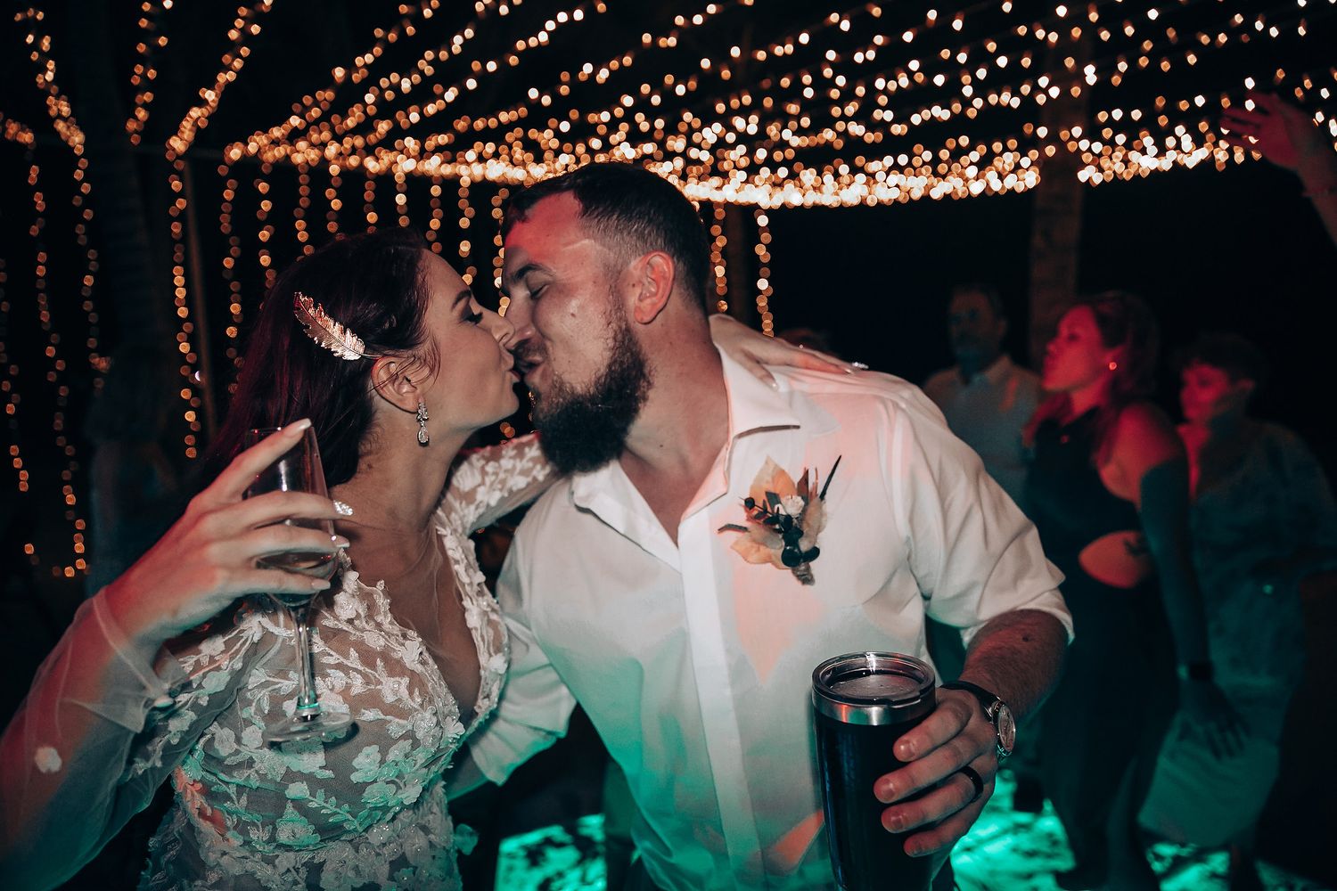 Newlyweds sharing intimate moment under twinkling lights at evening reception.