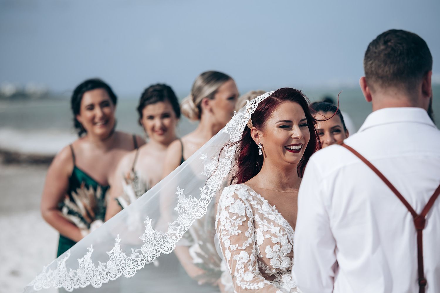 Emotional beach wedding ceremony with guests watching as couple exchanges vows.