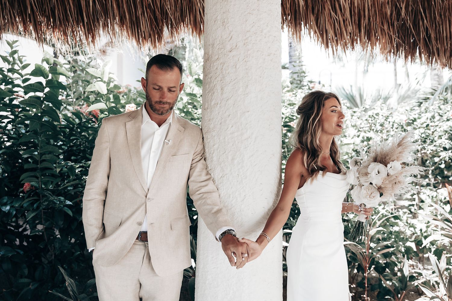 A couple is holding hands and walking together in a tropical setting.