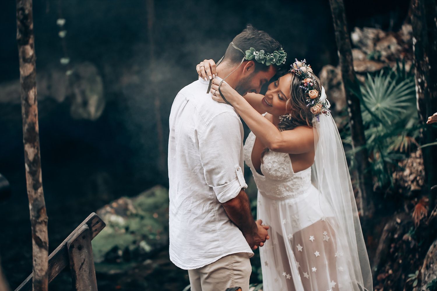 A romantic wedding couple embracing in a lush garden setting with natural lighting and greenery.