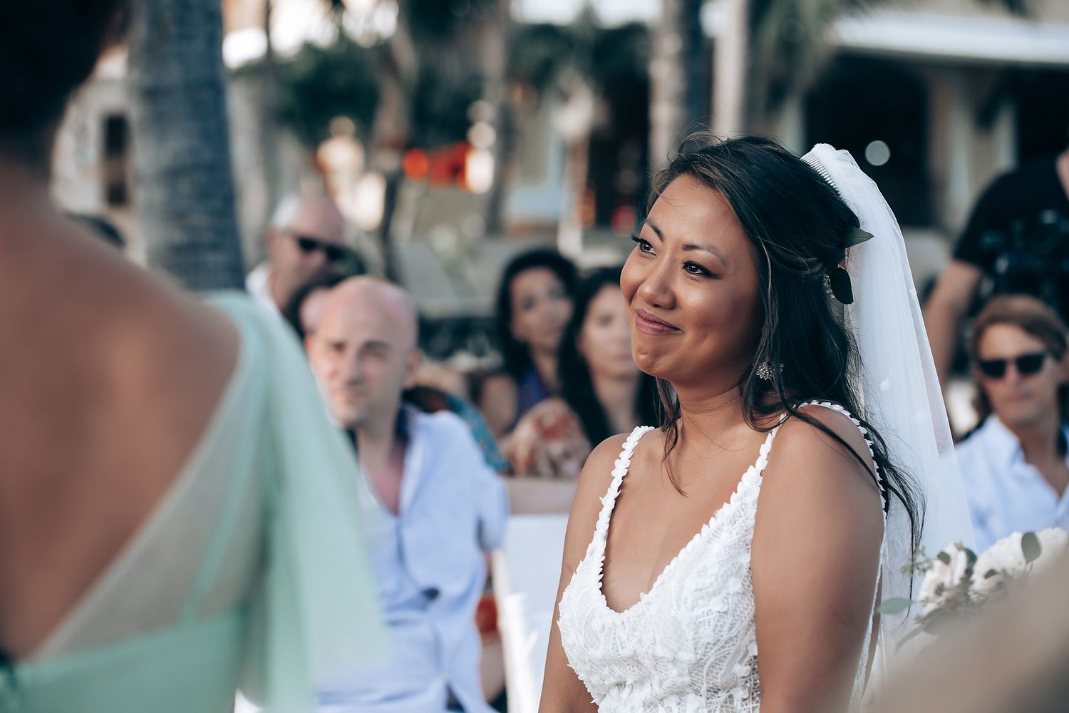 Wedding celebration on a tropical beach with guests in formal attire.