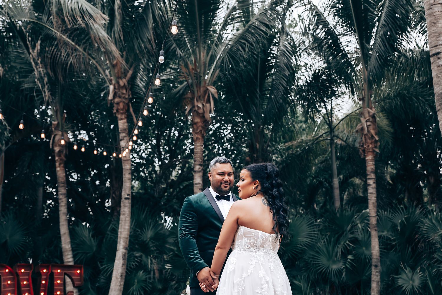 Palm tree-lined wedding venue with natural outdoor ceremony setting.