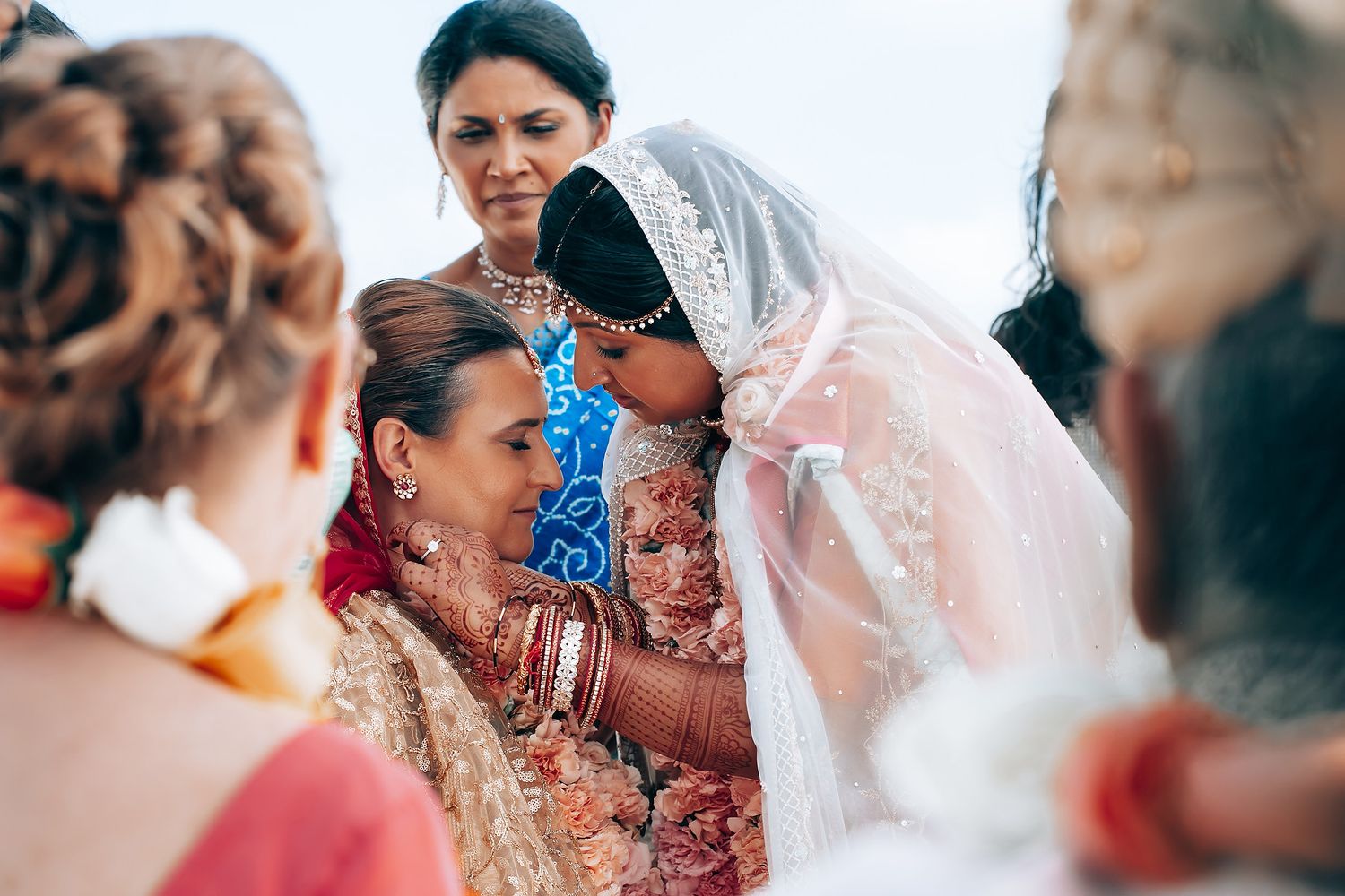 Intimate moment during a multicultural wedding ceremony with guests looking on.