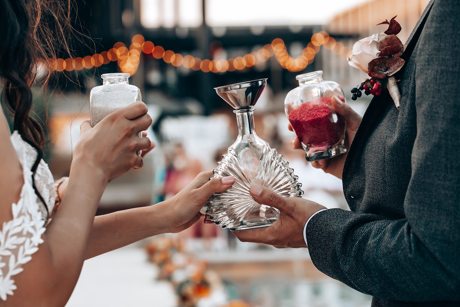 Wedding reception guests toasting with wine glasses under string lights.
