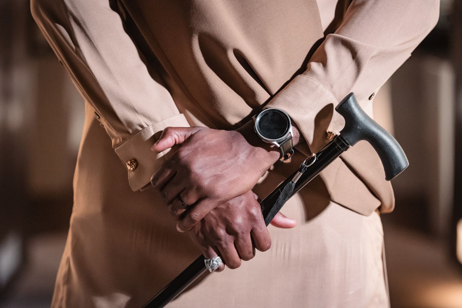 Close-up of groom holding walking cane with watch and bracelet visible during wedding ceremony.