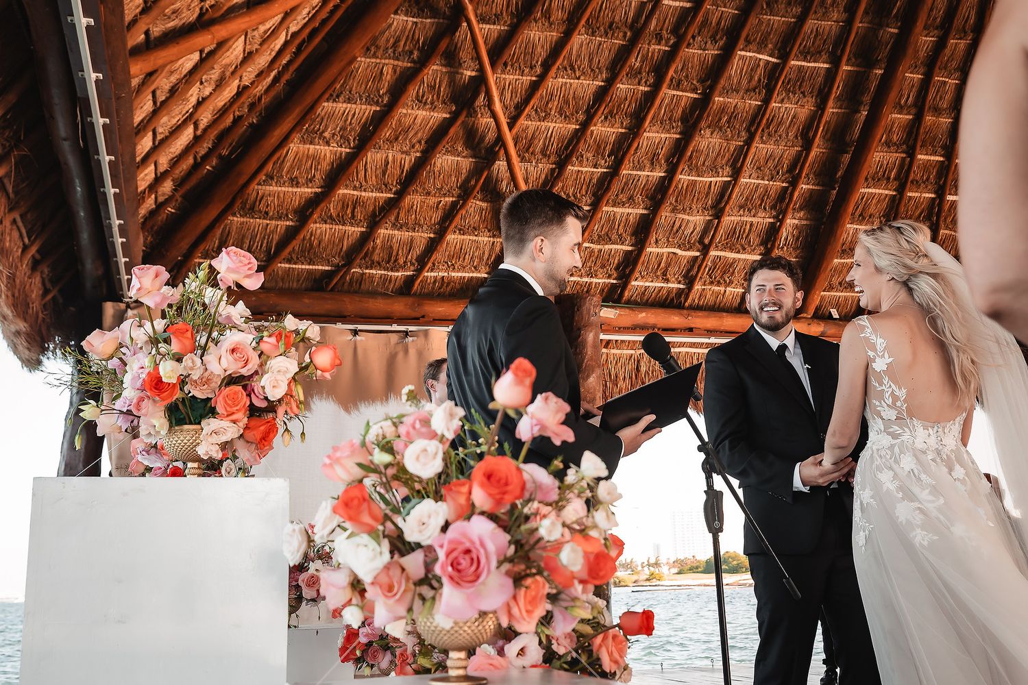 Wedding ceremony progression under tropical palapa with floral decorations.