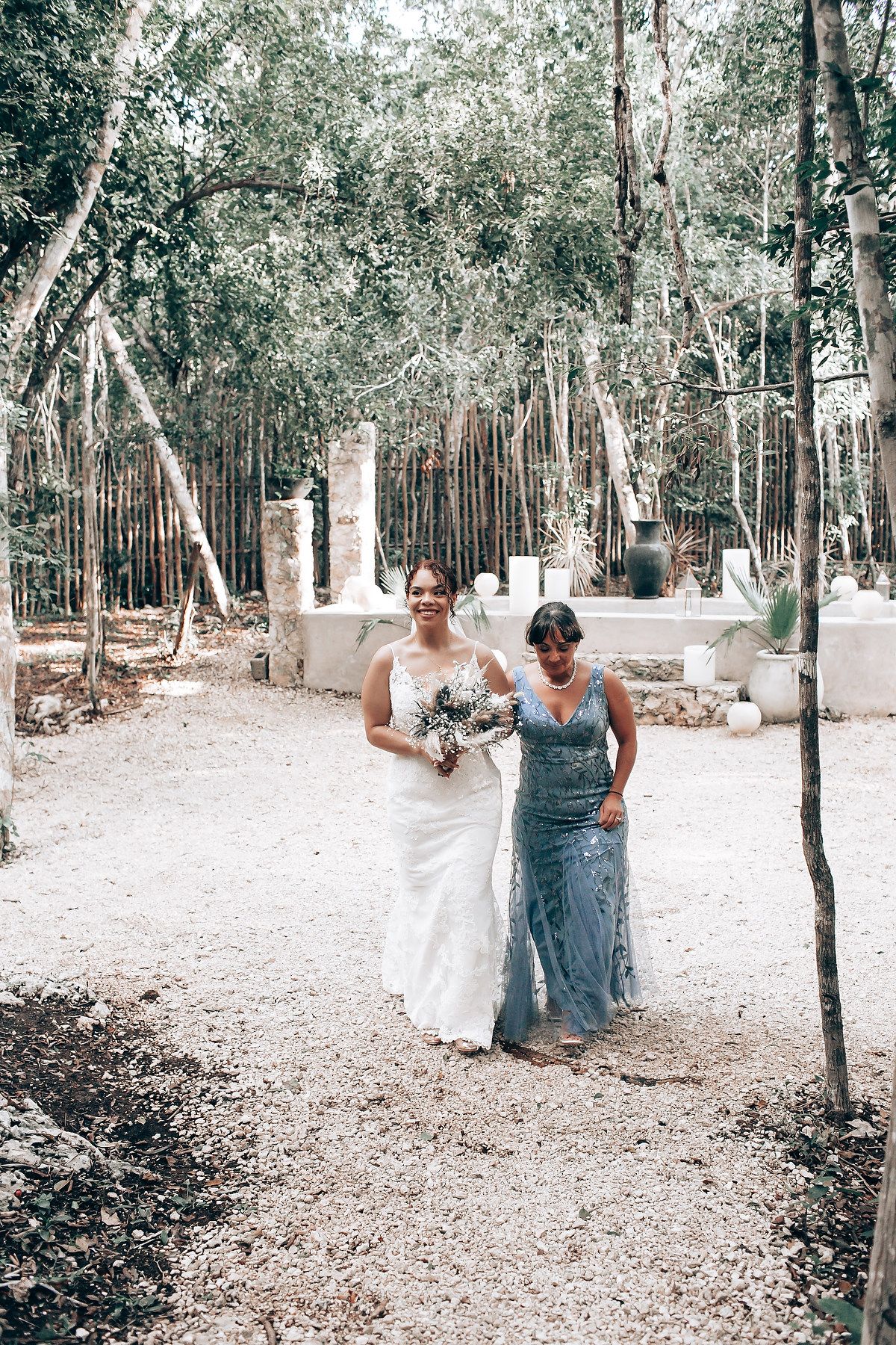 Wedding party walking along a tree-lined path in an outdoor forest venue.