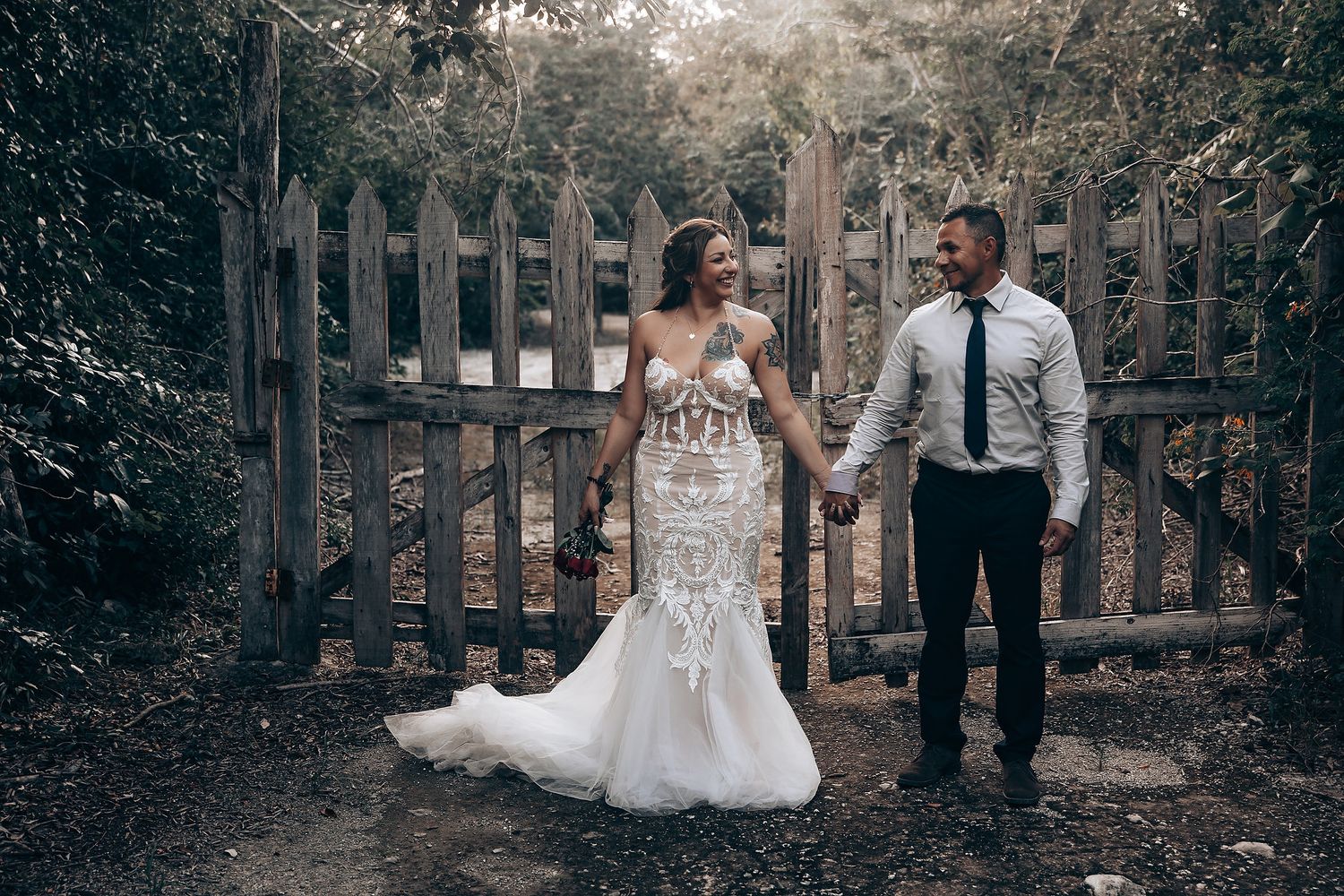 A romantic woodland wedding photoshoot with couples posing against rustic fencing.