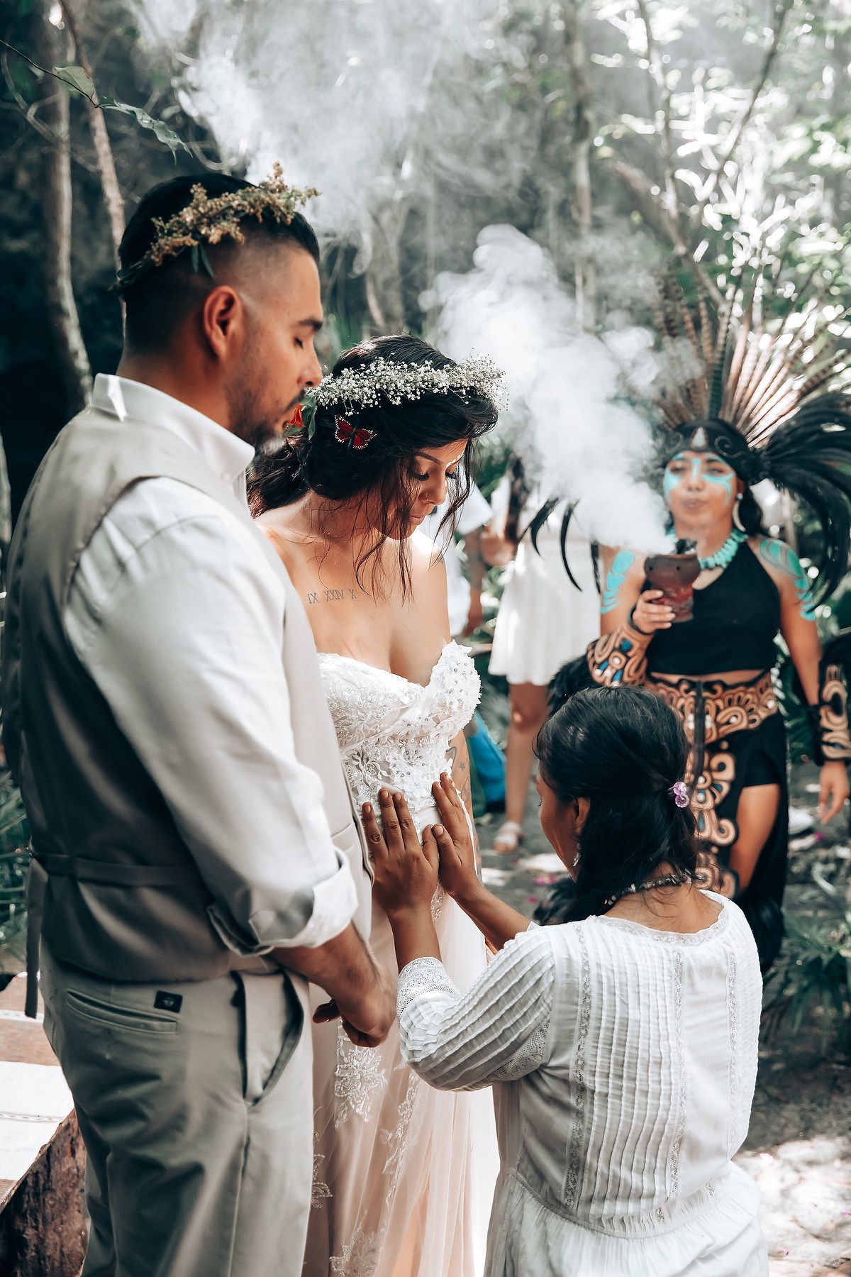 Wedding guests gather in a misty outdoor setting with ceremonial smoke rising.
