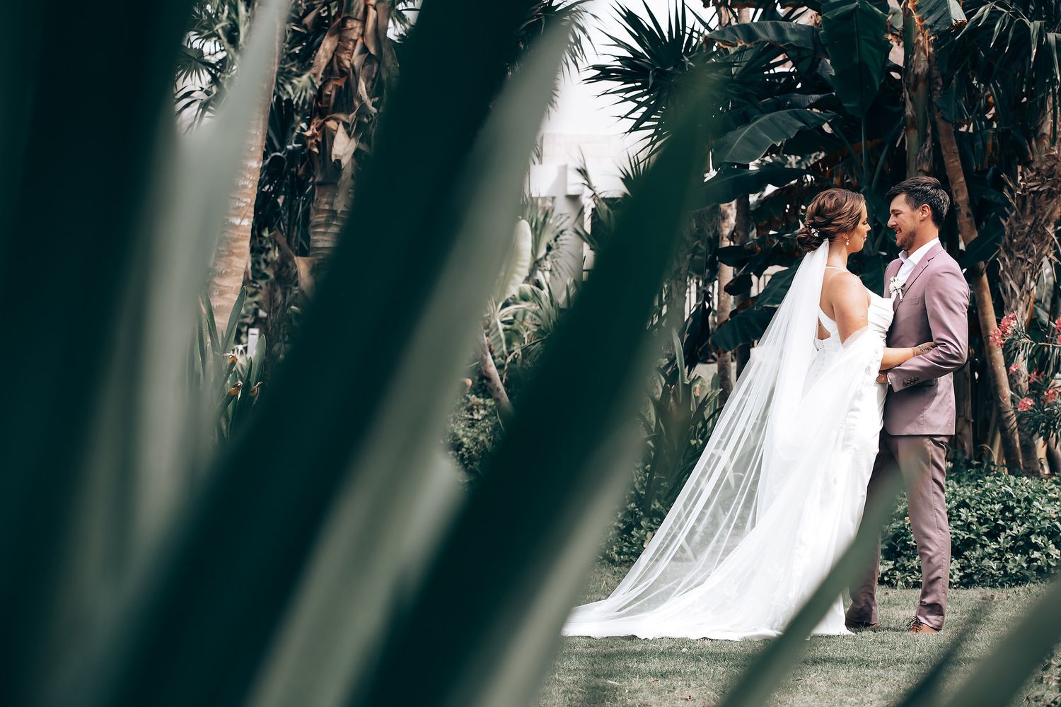 Wedding couple shares an intimate moment in a tropical garden setting.