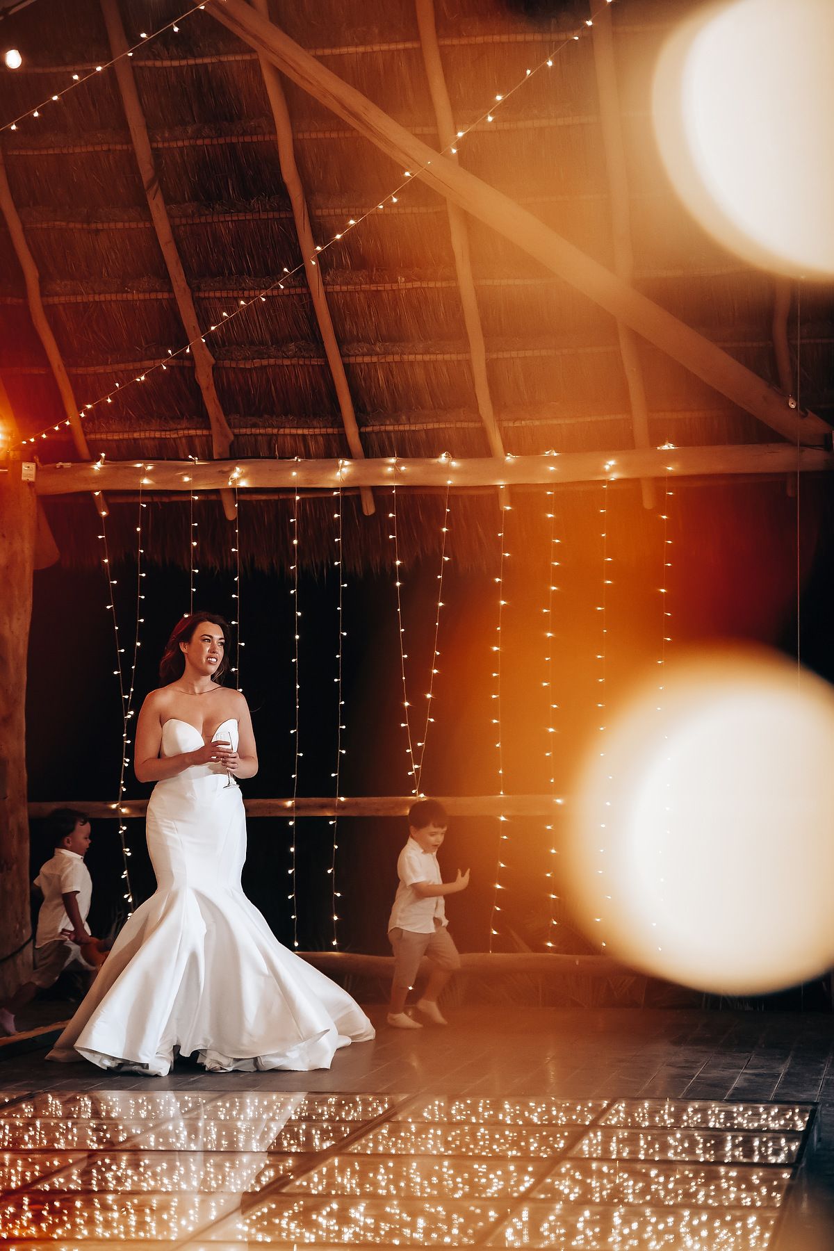 A wedding celebration in a warmly lit barn venue with fairy lights creating a magical atmosphere.