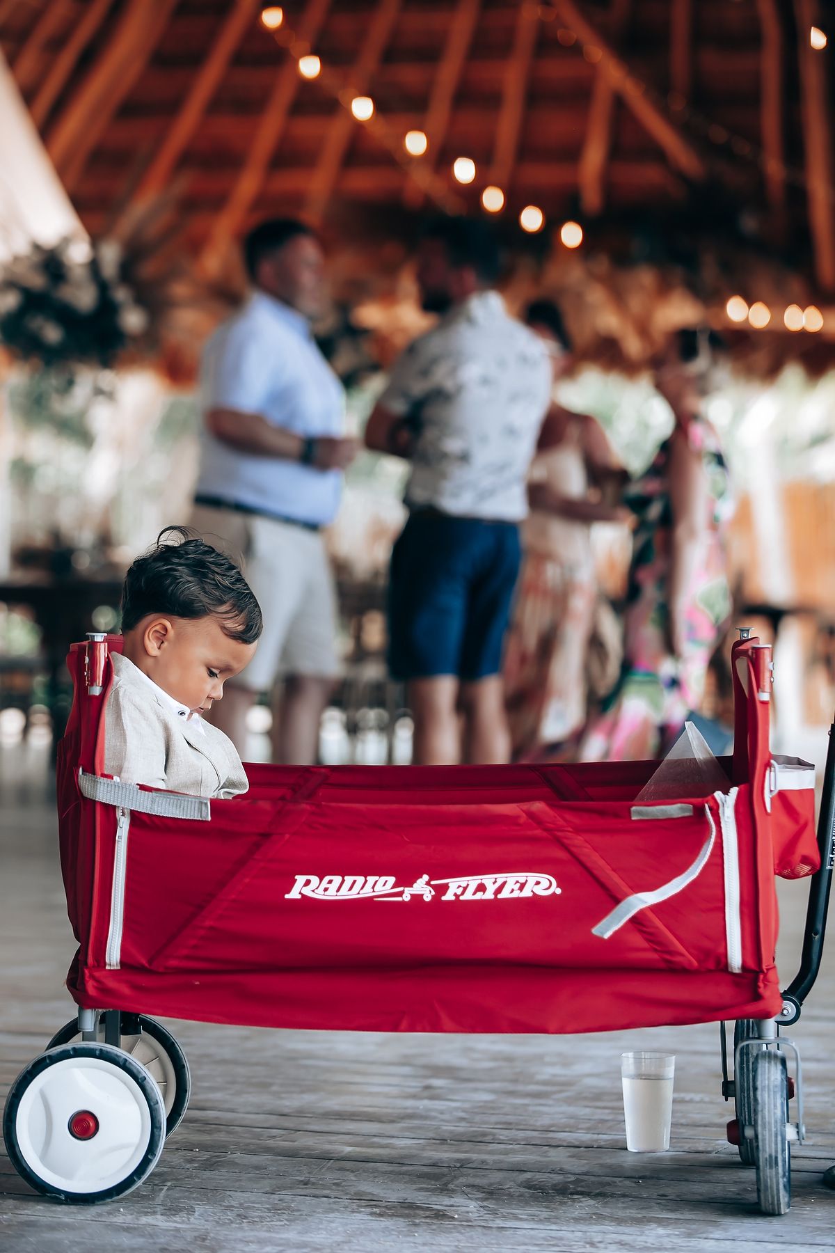 Red Radio Flyer wagon shown from different angles on a wooden floor with string lights in the background.