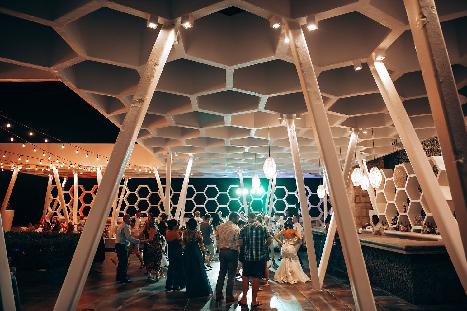 Modern honeycomb ceiling design illuminated with warm lighting at wedding venue.