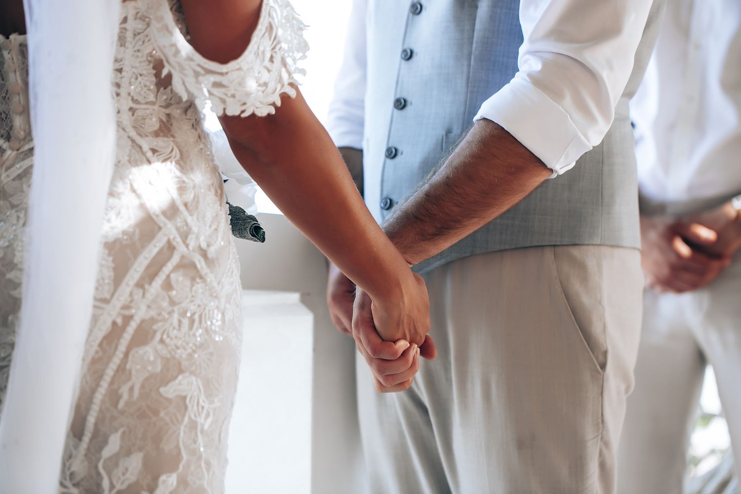 Elegant white wedding attire details with intricate lace patterns in natural lighting.