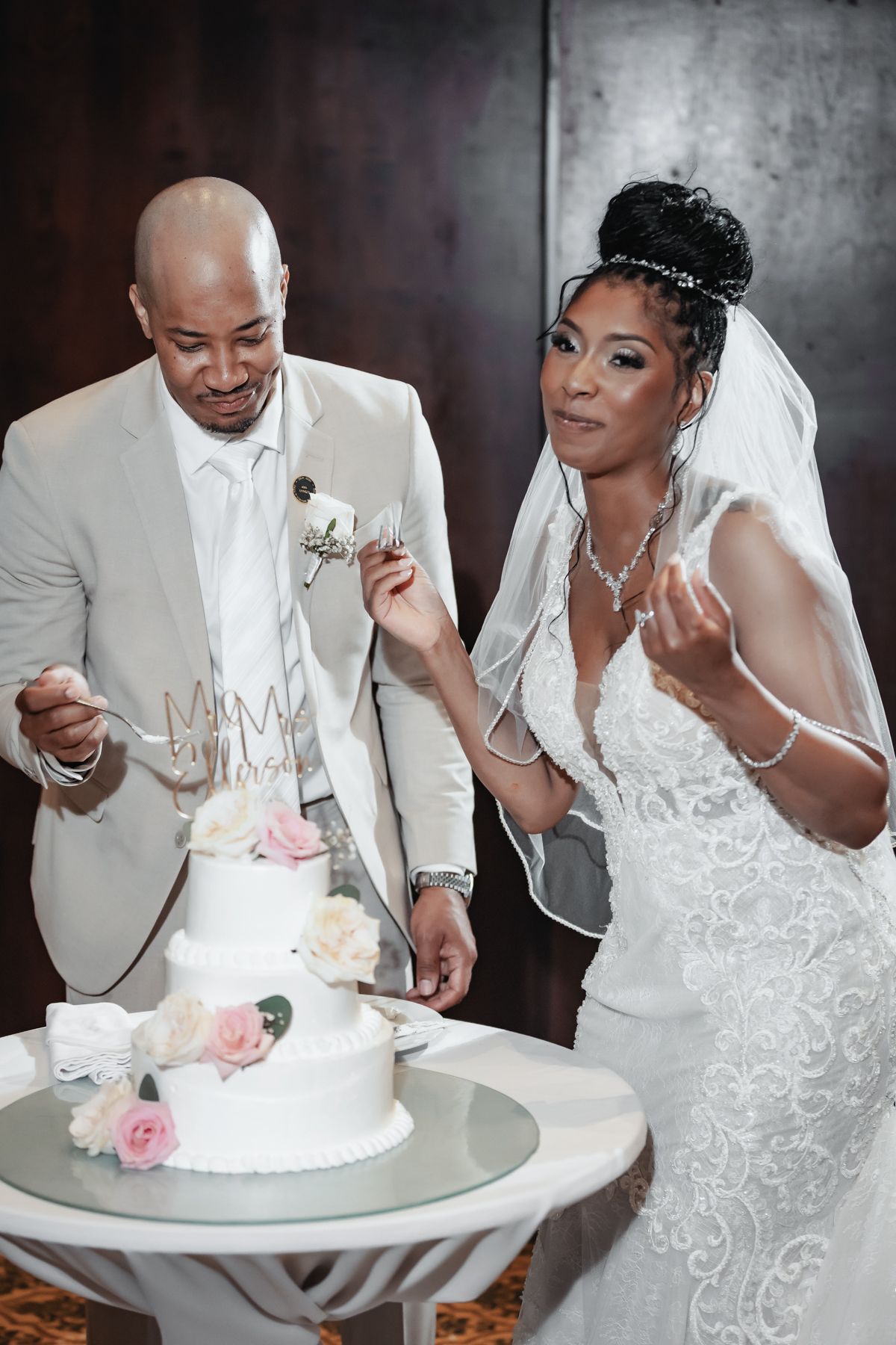 Bride and groom cutting their white wedding cake with floral decorations during their wedding reception ceremony.