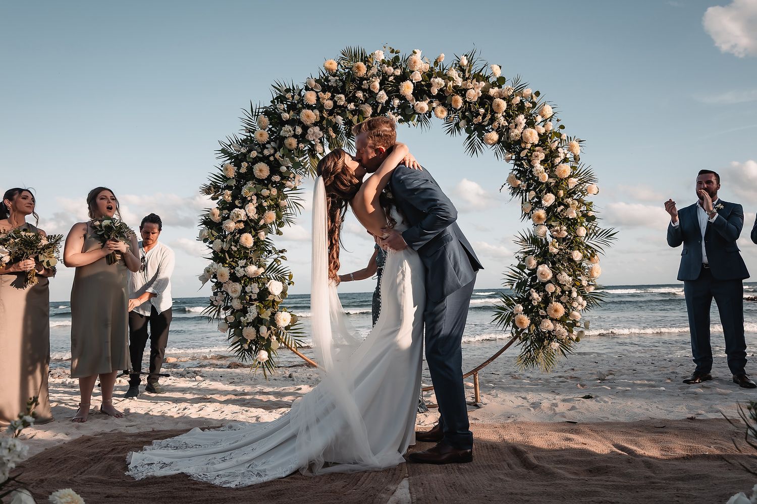 Wedding ceremony moments captured on beach with floral arch and celebrating guests.