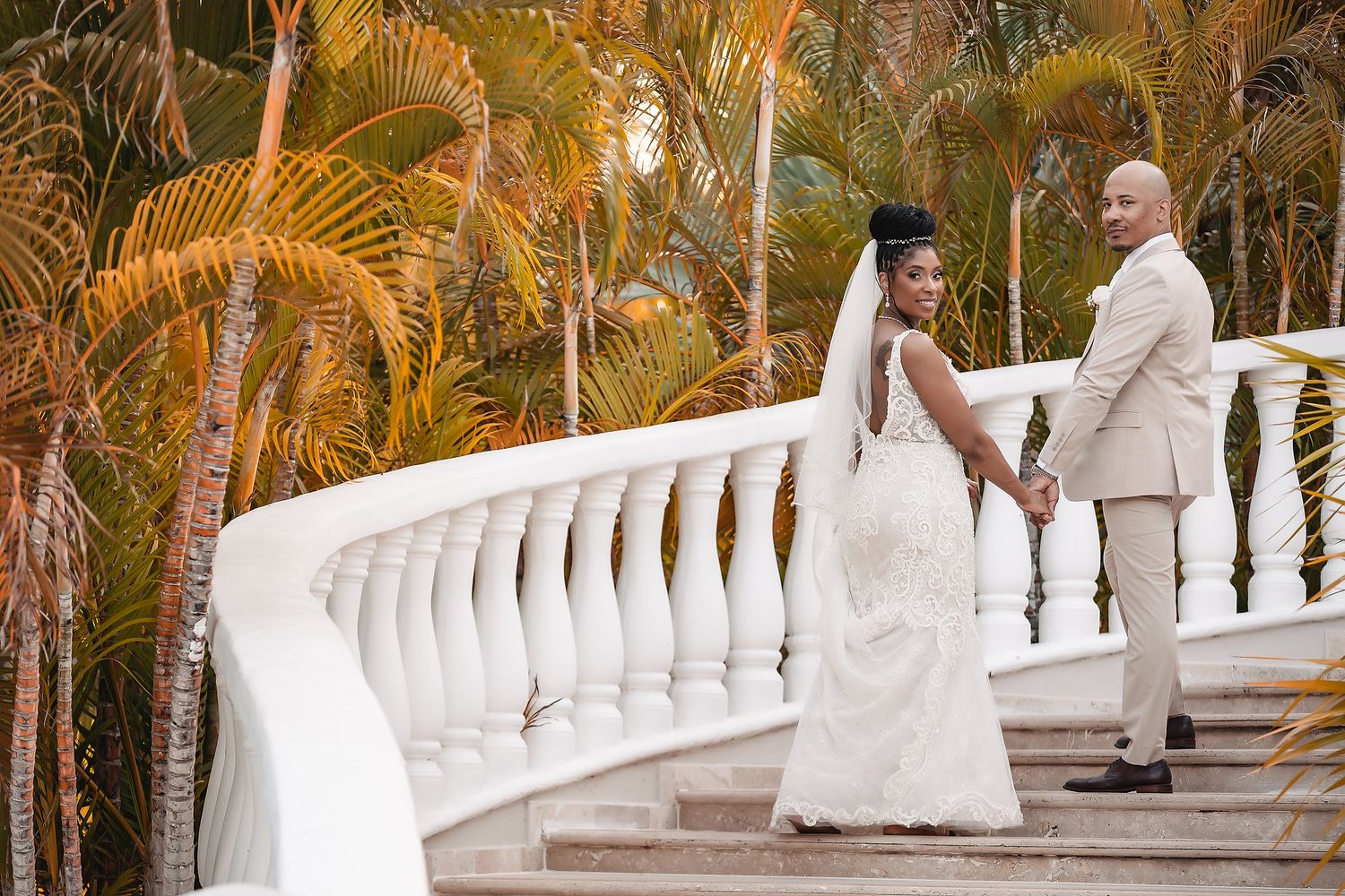 Elegant white balustrade staircase surrounded by tropical palm trees at a luxury resort venue.