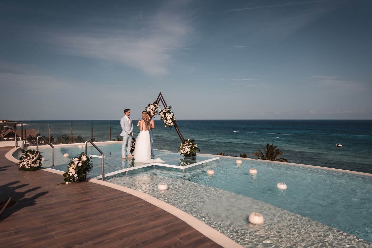 Modern infinity pool overlooking the ocean with wedding ceremony setup.