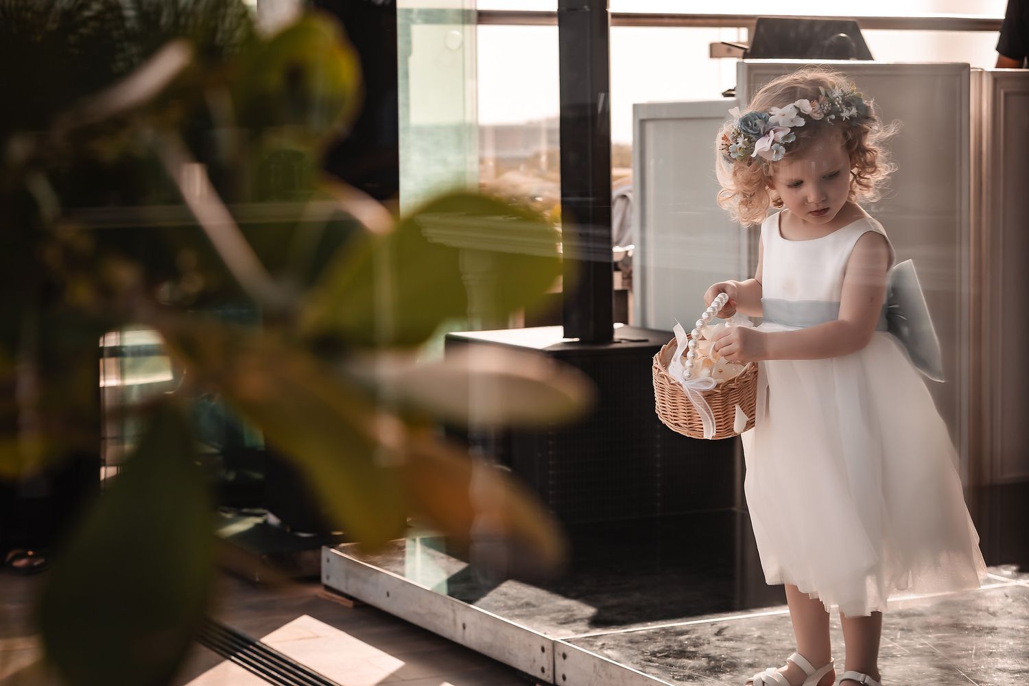 Small children in formal attire gather near decorative wedding details indoors.