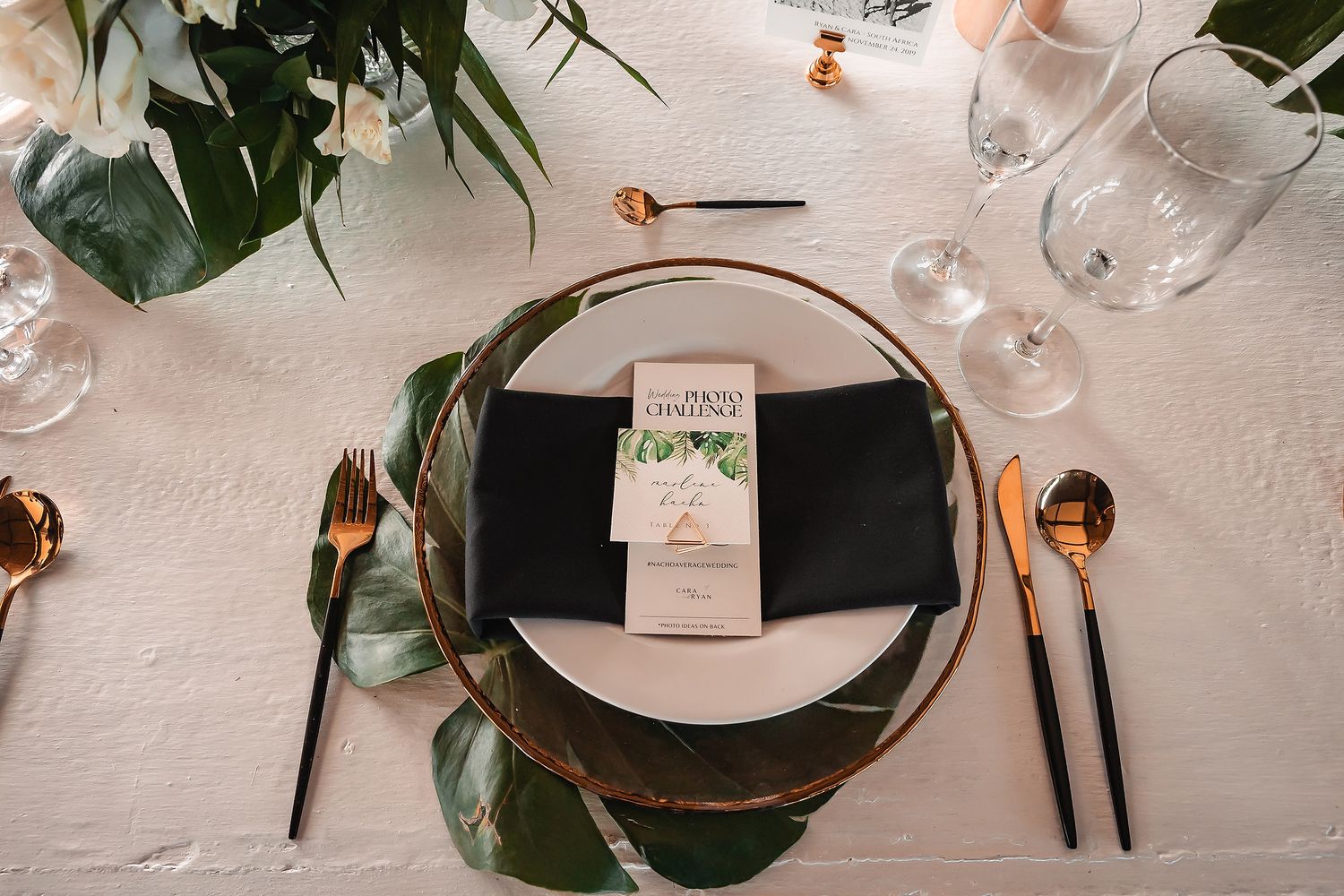 Close-up of wedding table setting with black napkins and delicate floral arrangements.