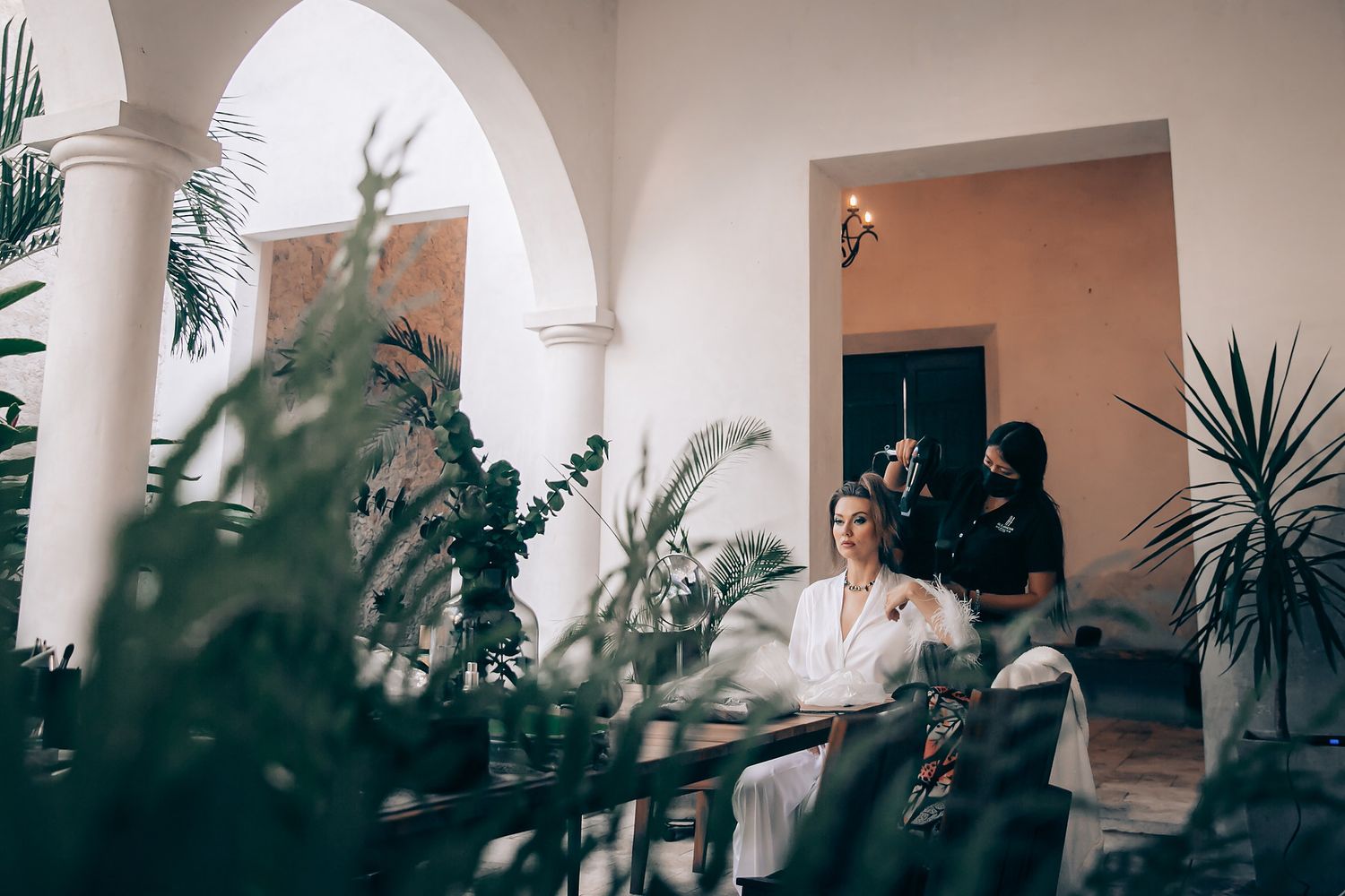 Architectural view through arched colonnade with palm plants and warm lighting creating Mediterranean ambiance.