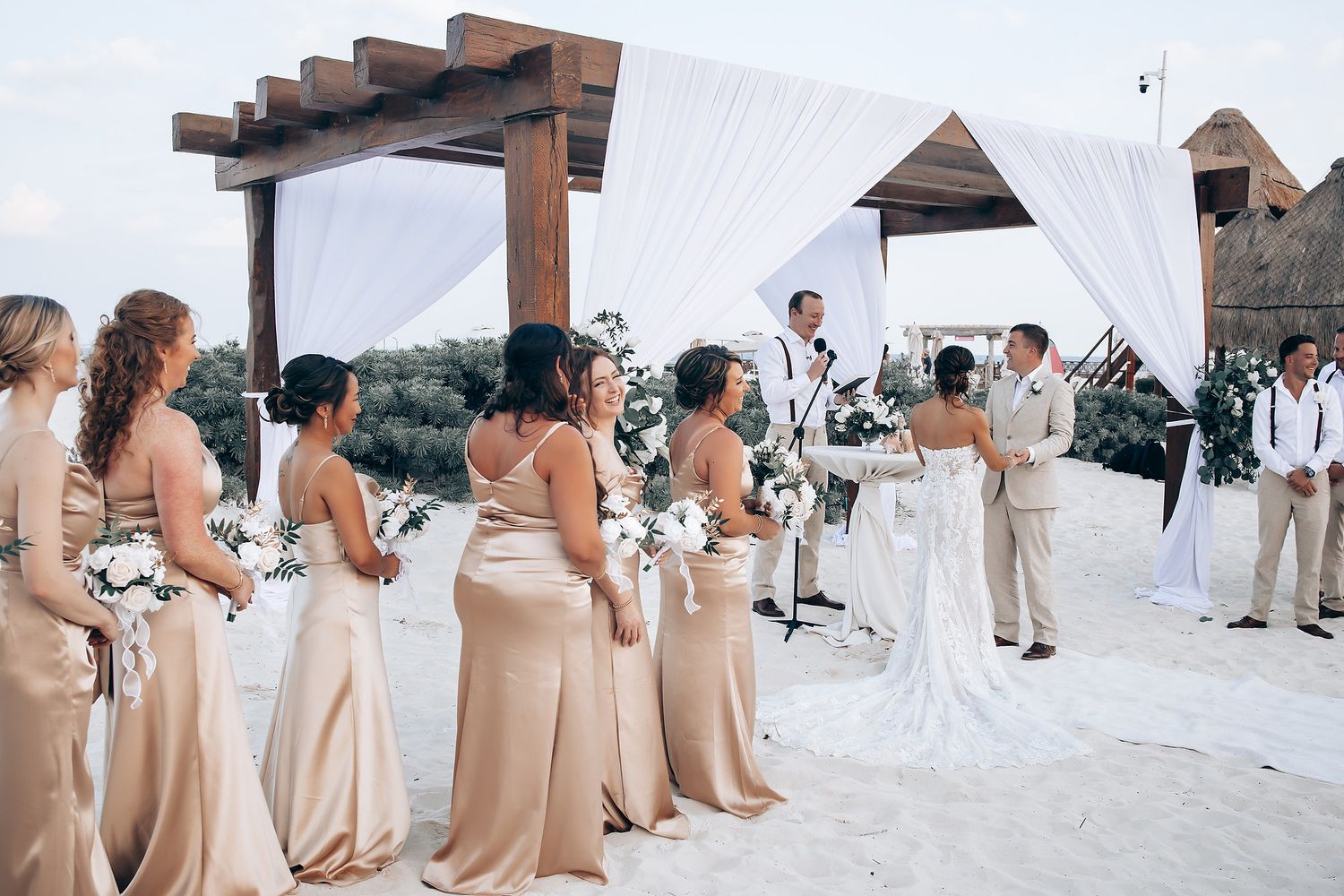 Wedding ceremony setup with white draping and wooden pergola overlooking the ocean.