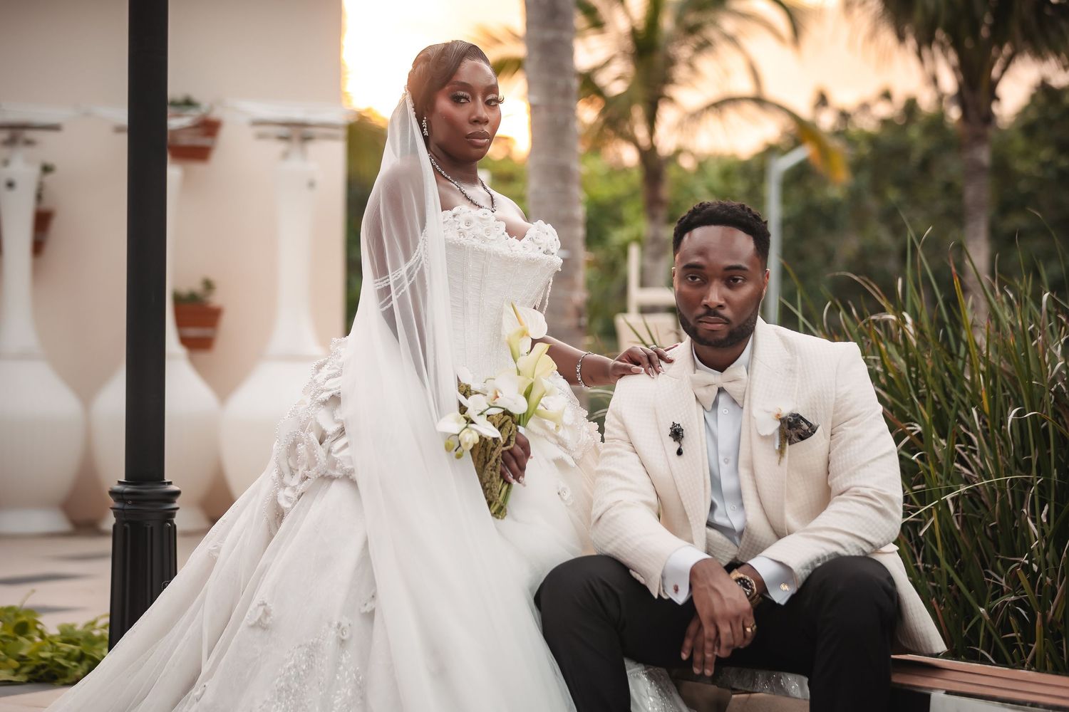 Stunning wedding portrait with tropical palm trees and white architecture in the background.