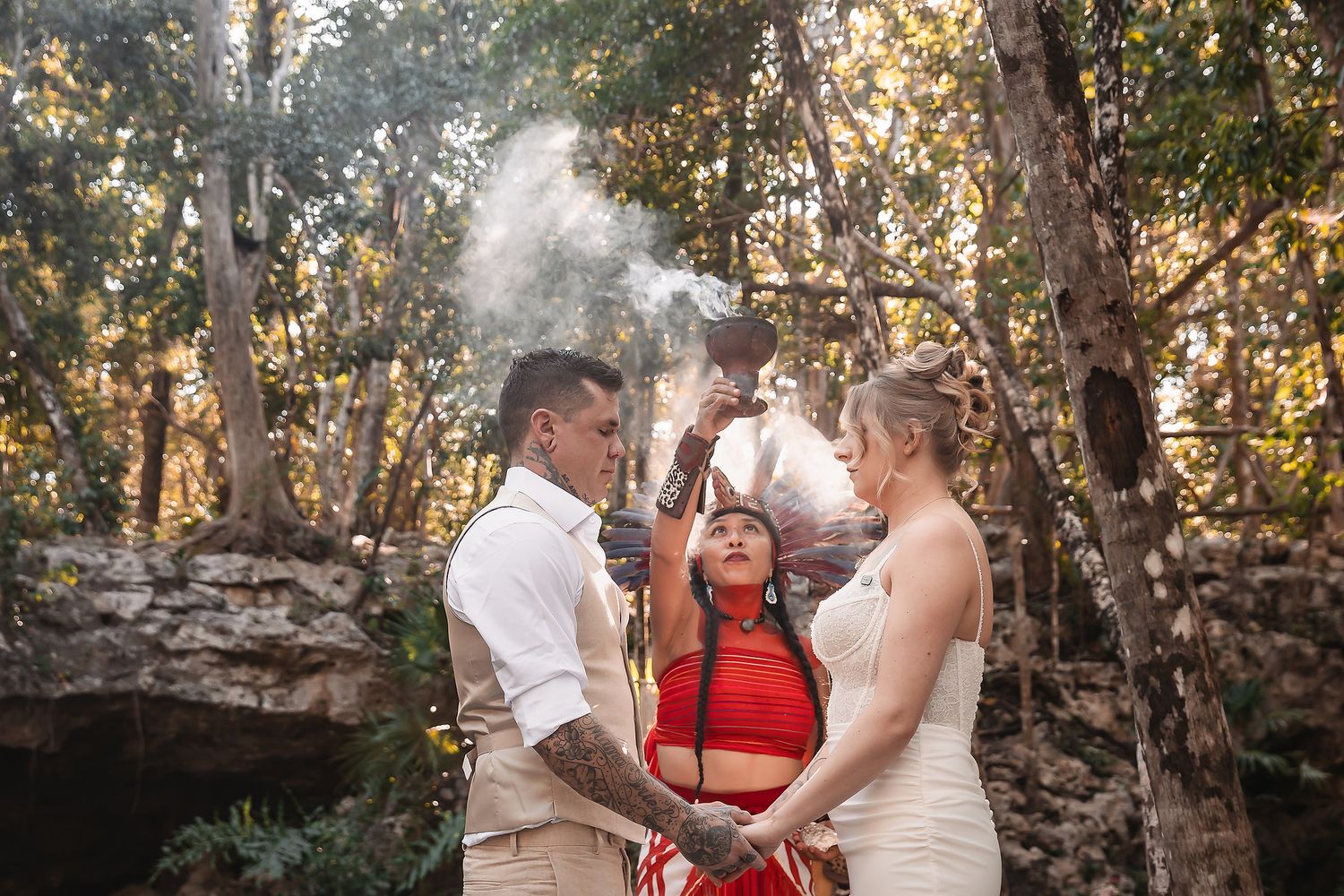 A wedding ceremony in a forest clearing with sunlight filtering through the trees.
